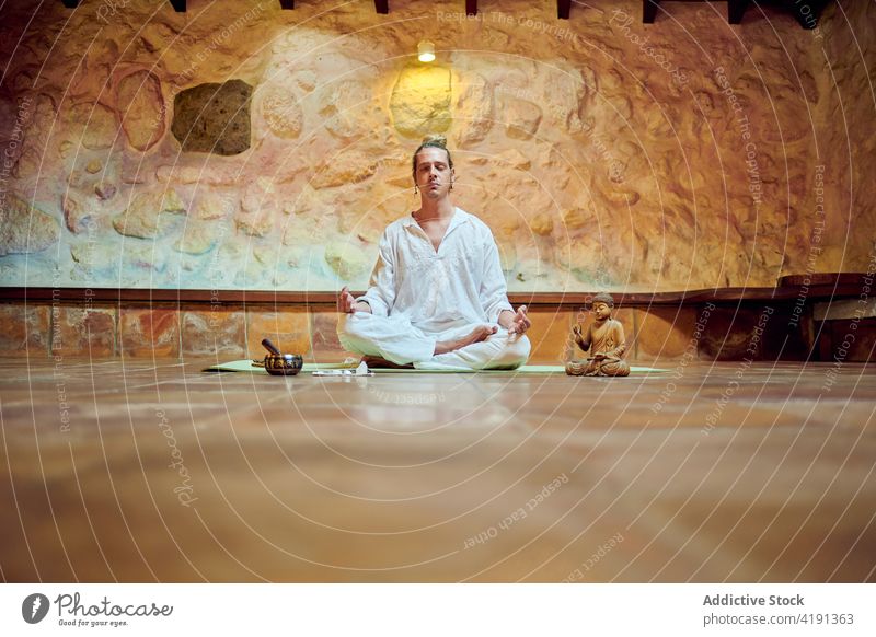 Achtsamer Mann meditiert in Lotus-Pose auf dem Boden Yoga meditieren Augen geschlossen Mudra Statuette Buddha Sprit Konzentration Kunst Bildhauerei Buddhismus