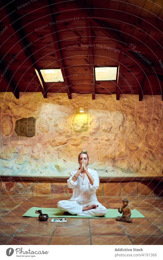 Achtsamer Mann meditiert in Lotus-Pose auf dem Boden Yoga meditieren Augen geschlossen Mudra Statuette Buddha Sprit Konzentration Kunst Bildhauerei Buddhismus