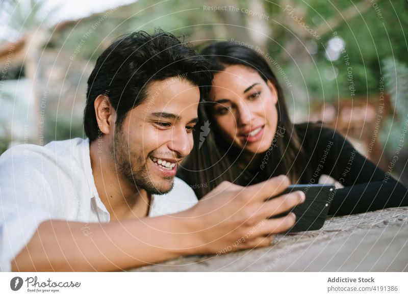 Junges Paar, das beim Spaß haben aufs Handy schaut Videoanruf Telefon Smartphone Menschen sitzen Internet Mobile Person Lifestyle Frau Mann jung