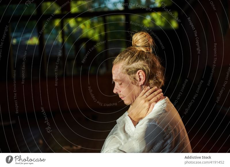 Verträumter Mann, der seinen Hals berührt, während er im Garten Yoga übt Tasthals meditieren üben Augen geschlossen Achtsamkeit Wohlbefinden Porträt Profil