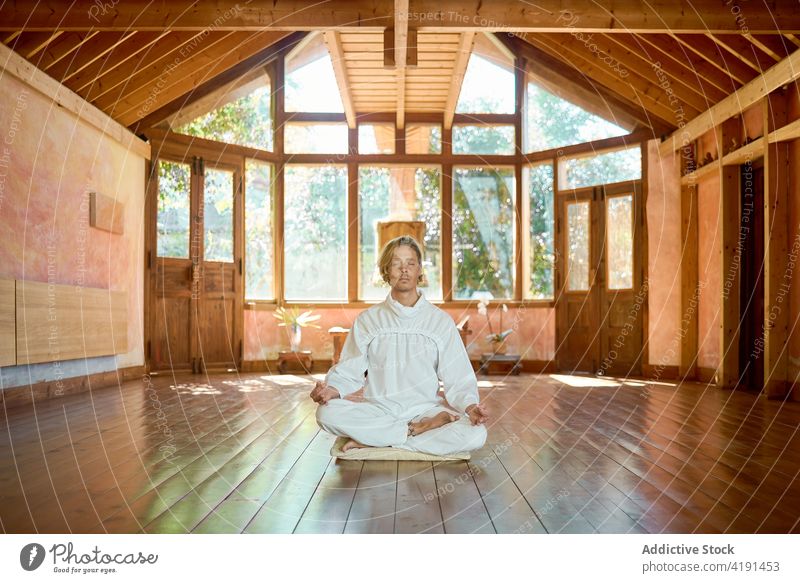 Mann meditiert in Lotus-Pose im Zimmer meditieren Yoga Dhyana Mudra Harmonie Stressabbau Sprit Stock Raum Stein Kultur ruhig Tradition Barfuß Dehnung idyllisch