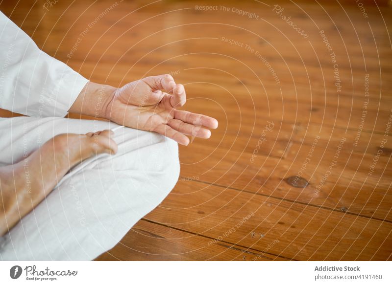 Crop-Mann meditiert und zeigt Mudra-Geste im Zimmer Yoga üben Sprit Meditation Harmonie Wellness Raum meditieren weiß Stoff zeigen Parkett Gelassenheit Energie