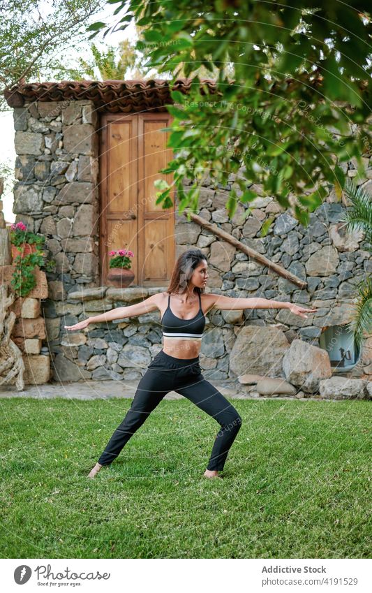 Frau demonstriert Krieger zwei Pose im Garten Yoga Gesunder Lebensstil beweglich virabhadrasana Dehnung Gleichgewicht üben Rasen Hof Wellness natürlich