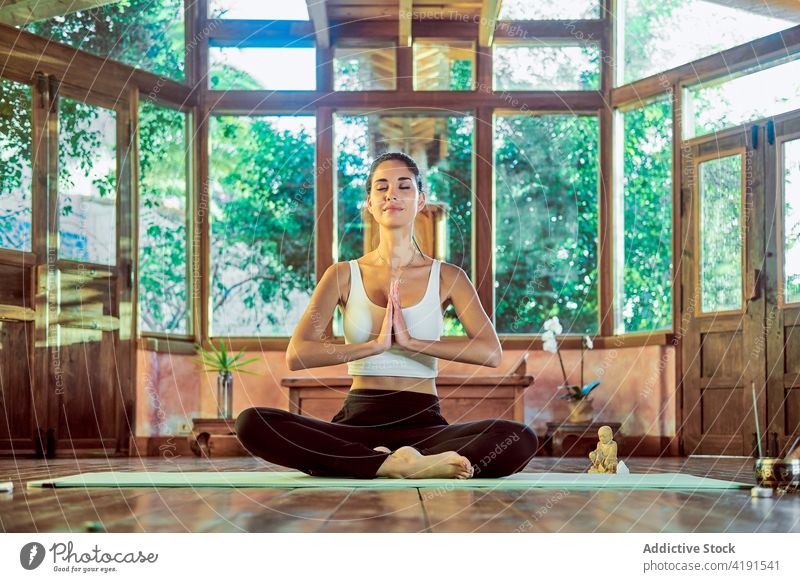 Achtsame Frau meditiert in Sukhasana-Haltung auf Yogamatte meditieren üben Beine gekreuzt Sprit Zen Stressabbau Augen geschlossen Haus Unterlage Wellness Barfuß