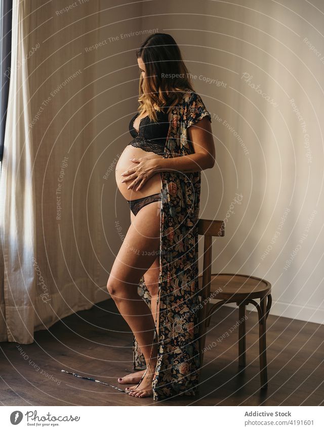 Schwangere Frau, die ihren Bauch berührt und nach unten schaut schwanger anonym Stil Bauch anfassen Mutterschaft pränatal erwarten Appartement Dessous Hut