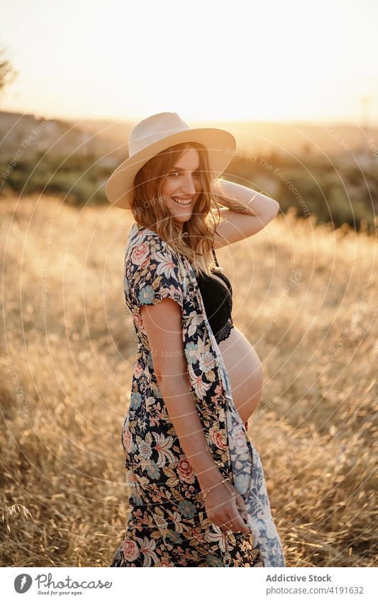 Schwangere Frau auf einem Feld auf dem Land stehend schwanger Natur Lächeln Landschaft mütterlich Glück Umwelt Hut Mutter friedlich Dessous Windstille tagsüber