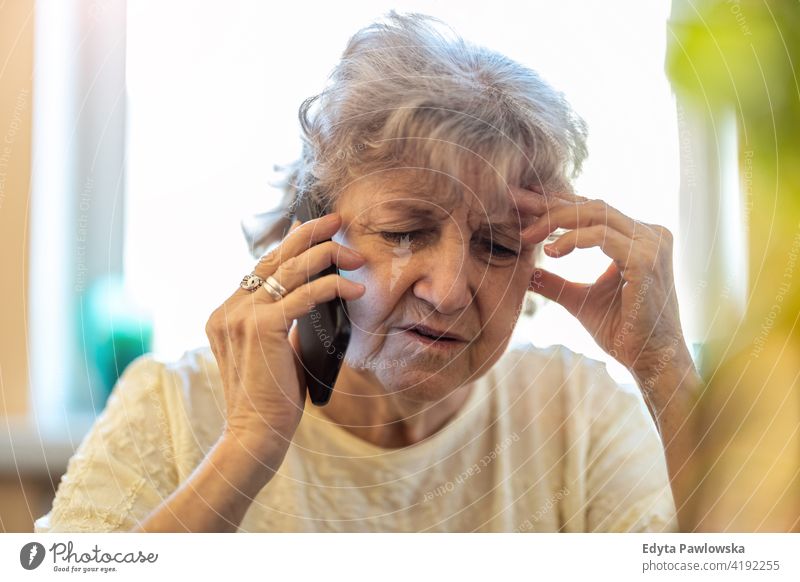 Aufnahme einer müden älteren Frau, die ein Mobiltelefon benutzt echte Menschen offen Senior reif Kaukasier heimwärts Haus alt Alterung häusliches Leben