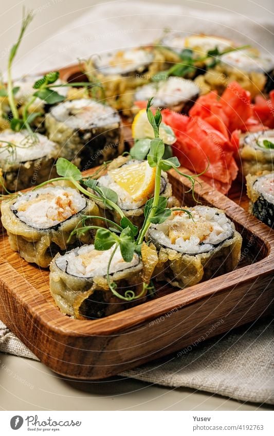 Nahaufnahme assortierte heiße Rollen mit Aal, japanischem Omelett, Frischkäse, Röstzwiebeln und Unagi-Sauce mit frischen Kräutern. Japanisches Essen auf einer Bambusplatte. Vertikale Aufnahme