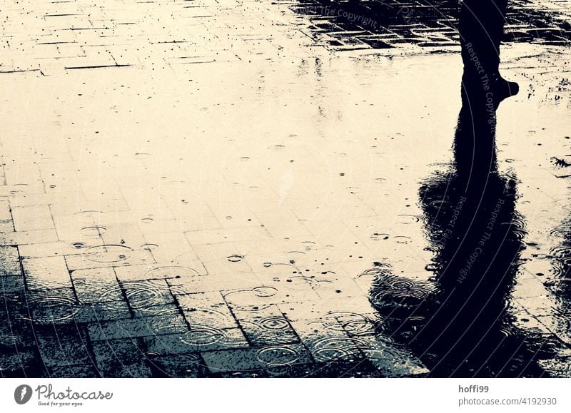 abstrakte Regenpfütze mit Mensch Pfütze Pfützenspiegelung Pfützenbild pladdern Regentropfen schlechtes Wetter Wassertropfen Natur Tropfen nass Pflastersteine