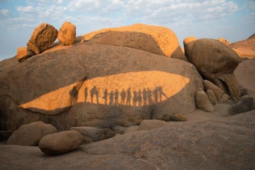 Felsen im Damaraland mit den Schatten einer Gruppe von Menschen an einem sonnigen Tag Namibia damaraland Menschengruppe genießen Glück Zusammensein wüst heiß