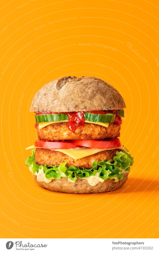 Veganer Burger Nahaufnahme isoliert auf einem orangefarbenen Hintergrund. alternativ Brot Käse Cheeseburger Farbe farbig Konsumverhalten Textfreiraum Küche