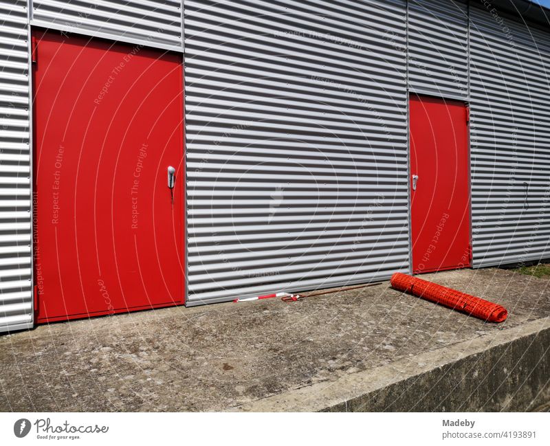 Rote Stahltüren für den Brandschutz in der silbern glänzenden Wellblechfassade eines Flugzeughangar in Oerlinghausen bei Bielefeld im Teutoburger Wald in Ostwestfalen-Lippe