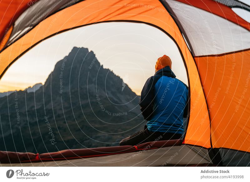 Reisender sitzt in der Nähe des Zeltes und genießt den Sonnenuntergang über den Bergen Berge u. Gebirge Morgen Sonnenaufgang Wanderer Wohnmobil Mann Ambitus