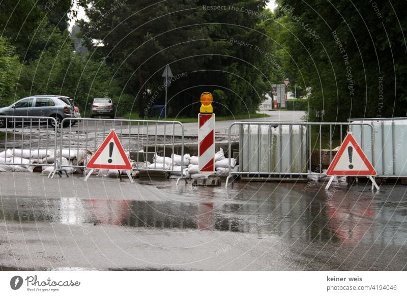 Eine überflutete Straße wurde gesperrt wegen Hochwasser nach Starkregen Wolkenbruch Gewitter Klima Klimawandel Warnschild Sperrung Barken Absperrgitter Autos