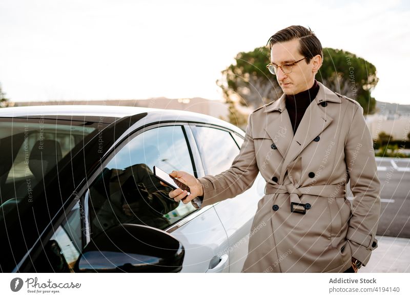 Geschäftsmann entriegelt Auto mit Smartphone aufschließen PKW Automobil Fernbedienung benutzend Unternehmer Tür App männlich Mann modern online Mobile Gerät
