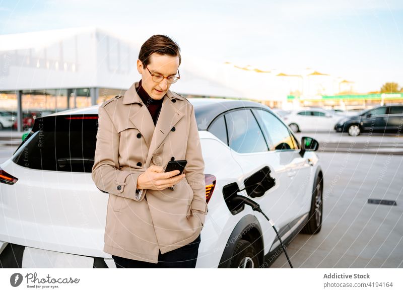 Geschäftsmann wartet an einer Tankstelle auf das Betanken seines Autos besetzen PKW Benzin Station Brennstoff Tülle Smartphone benutzend männlich Mann