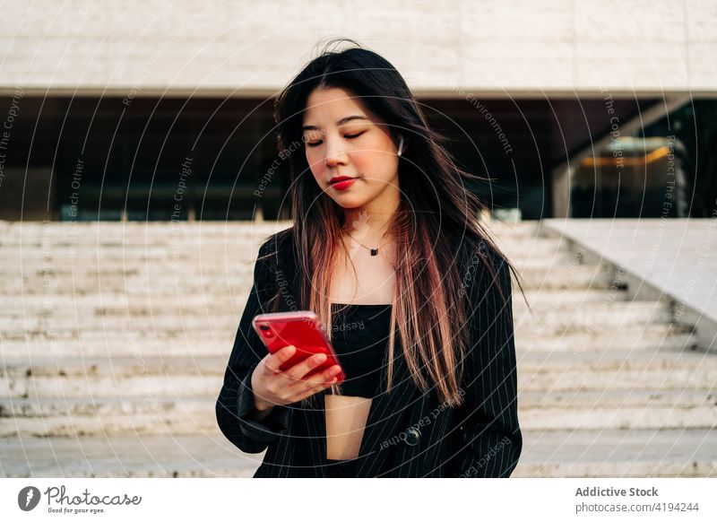 Langhaarige brünette asiatische Frau benutzt Handy auf der Straße Funktelefon Chinesisch Mobile Telefon Japanisch Smartphone Mädchen Glück Menschen jung eine