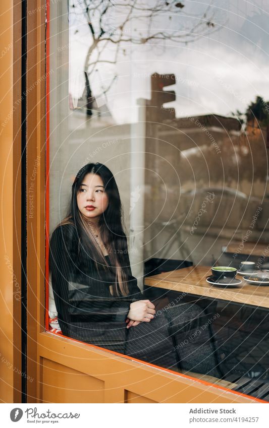 Langhaarige brünette asiatische Frau trinkt einen Kaffee in einem Café Menschen Werkstatt Chinesisch Kaffeehaus Tasse Person trinken heiß lange Haare