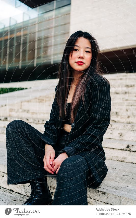 Lange Haare brünette asiatische Frau sitzt auf einer Treppe und schaut in die Kamera Japanisch Asien jung Model Chinesisch Stil attraktiv Dame Straße modern