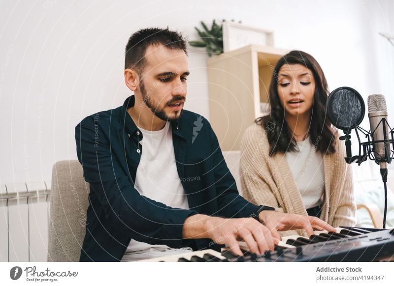 Ehepaar nimmt zu Hause ein Lied auf Aufzeichnen Gesang heimwärts Paar singen spielen Synthesizer Musik Musiker Zusammensein Sänger Mikrofon Klang Audio Probe
