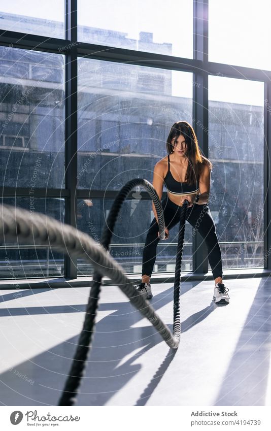 Aktive Frau beim Training mit Kampfseilen im Fitnessstudio Sportlerin Athlet Seil Ausdauer anstrengen stark Kraft intensiv Schlacht Übung Wohlbefinden