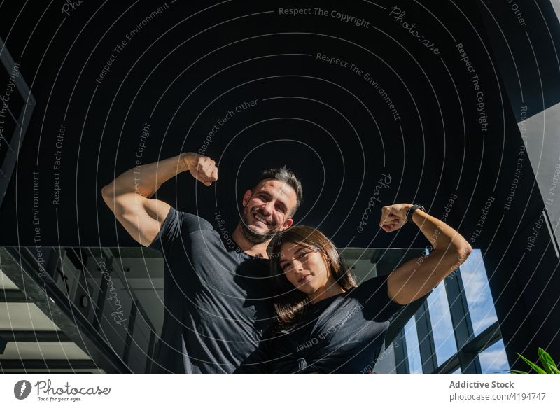 Positives starkes Paar zeigt Bizeps im Fitnessstudio Bodybuilder Muskel zeigen flex Optimist Umarmung Kraft Stärke Sport Sportler Sportlerin Bodybuilding