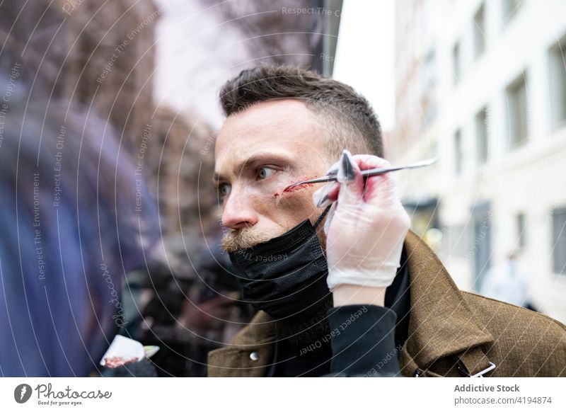 Anonymer Maskenbildner, der das Gesicht eines Hipsters schminkt zusammenstellen Vollbart Mann bärtig Mode jung männlich Porträt Typ Kaukasier Schönheit