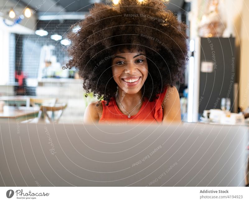 Ethnische Frau arbeitet an einem Laptop in einem Café freiberuflich Browsen abgelegen Entfernung heiter Afro-Look Frisur schwarz Afroamerikaner Netbook online