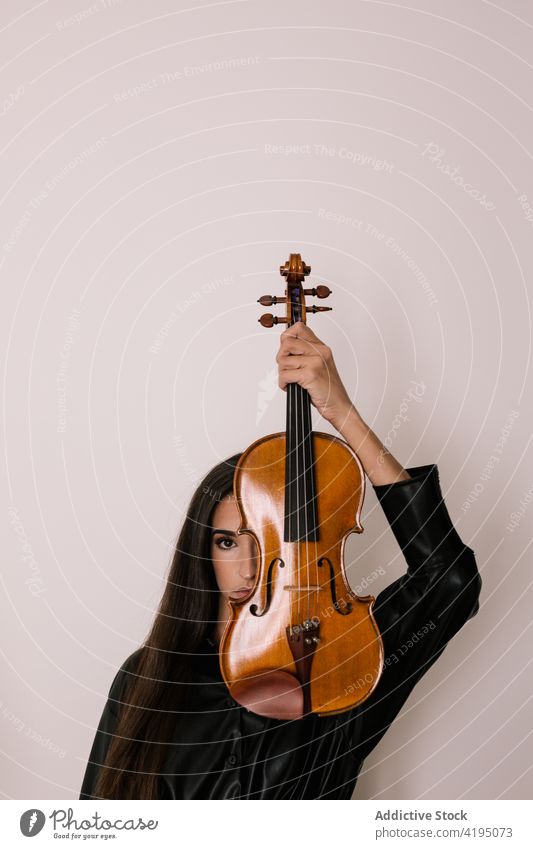 Musiker versteckt sich hinter Geige im Studio Frau Spieler akustisch Hobby Melodie Deckblatt Kunst Tierhaut Künstler professionell Talent Fähigkeit Instrument