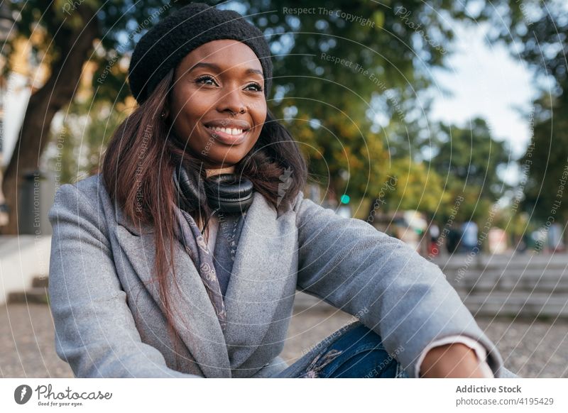 Gelassene ethnische Frau entspannt in der Stadt Straße Denken nachdenklich Großstadt Lächeln charmant verträumt Oberbekleidung schwarz Afroamerikaner Wachtraum