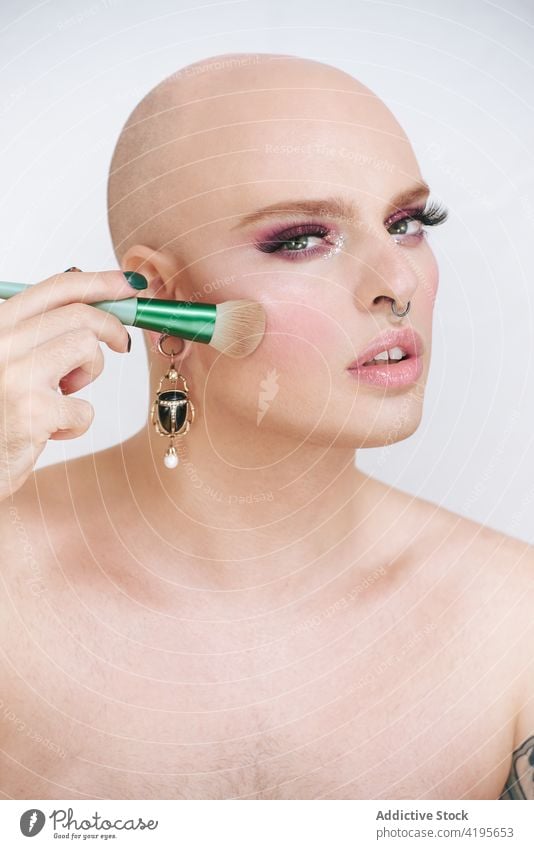 Queer mit verschiedenen Schminkpinseln auf weißem Hintergrund Transgender Mann Bürste Kosmetik Make-up Schönheit Tattoo feminin Werkzeug Porträt sortiert
