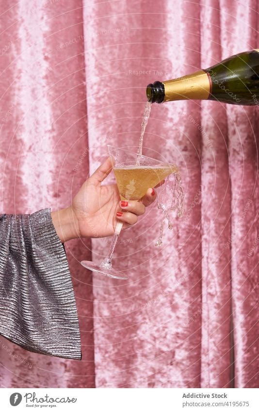 Crop Frau mit Glas Champagner in der Nähe von Samt Vorhang Flasche eingießen festlich feiern Alkohol trinken Gardine Getränk alkoholisch durchsichtig fließen
