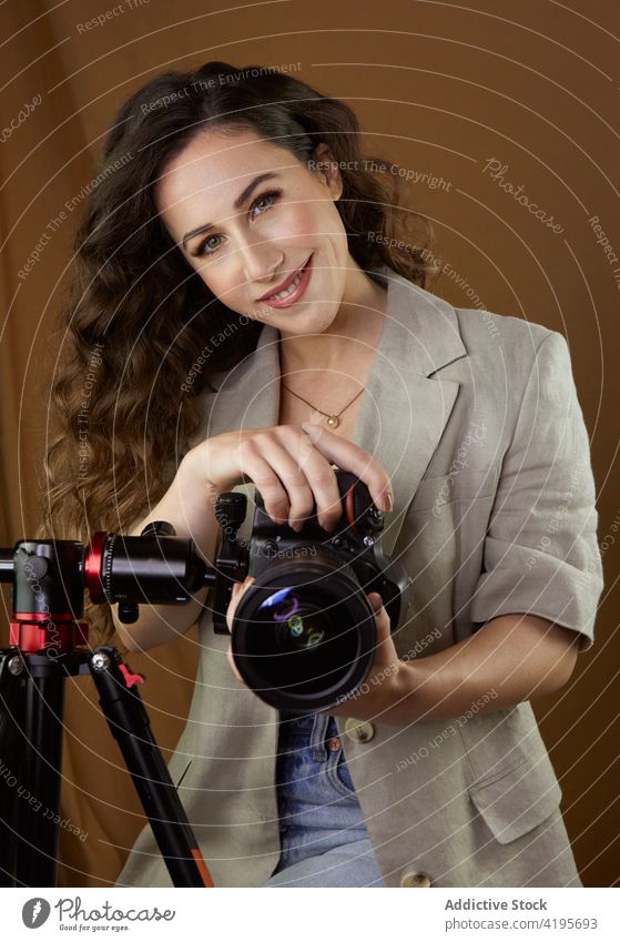 Positive junge Frau, die Bilder mit einer professionellen Kamera während einer Fotosession im Studio macht fotografieren Fotoapparat Glück Lächeln Fotograf