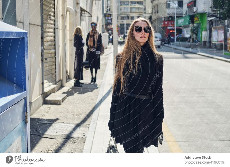 Trendige Frau auf städtischer Straße gegen anonyme multiethnische Freundinnen Frauen Stil Individualität Mode feminin charmant modern Sonnenbrille Stadt Revier