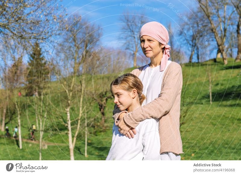 Kranke Mutter umarmt Tochter im Park Frau Zusammensein Krebs Liebe nachdenklich Partnerschaft Sommer Umarmen Krankheit Eltern sich[Akk] entspannen Konzept rosa
