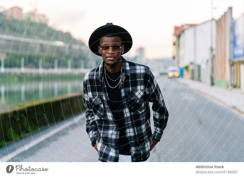 Stilvoller schwarzer Mann mit Hut auf einer Straße in der Stadt Mode Individualität cool maskulin Macho Afroamerikaner ethnisch Jeanshose kariertes Hemd