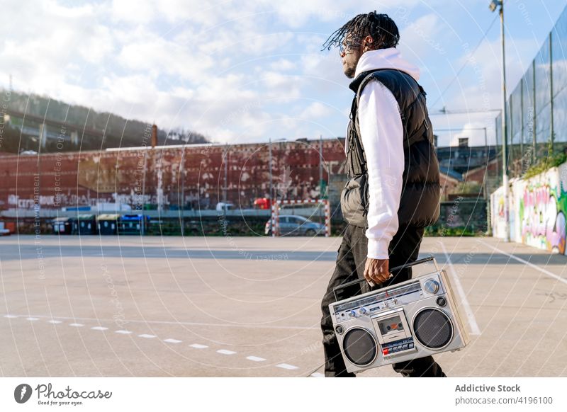 Schwarzer Hipster-Mann mit Retro-Kassettenrekorder auf städtischem Bürgersteig Schreiber retro Stil Hip-Hop Subkultur Straßenbelag urban führen Spaziergang