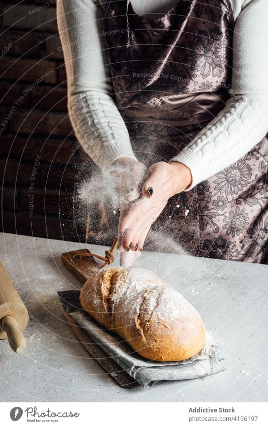 Bäcker beim Bestreuen eines Brotlaibs mit Mehl in einer Bäckerei Kunstgewerbler bestäuben Staubwischen gebacken kulinarisch Rezept Frau geschmackvoll natürlich