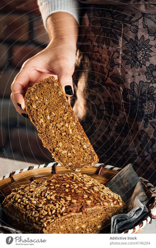 Getreidehandwerker zeigt geschnittenes Mehrkornbrot in der Backstube Bäcker Brot Müsli Nährstoff Protein frisch knackig lecker Frau Bäckerei weich Tisch
