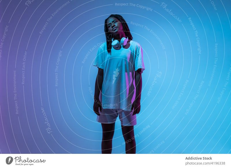 Schwarze jugendliche Tänzerin mit Kopfhörern im Studio Mädchen Teenager Licht Körperhaltung leuchten Youngster neonfarbig cool glühen Generation urban Atelier