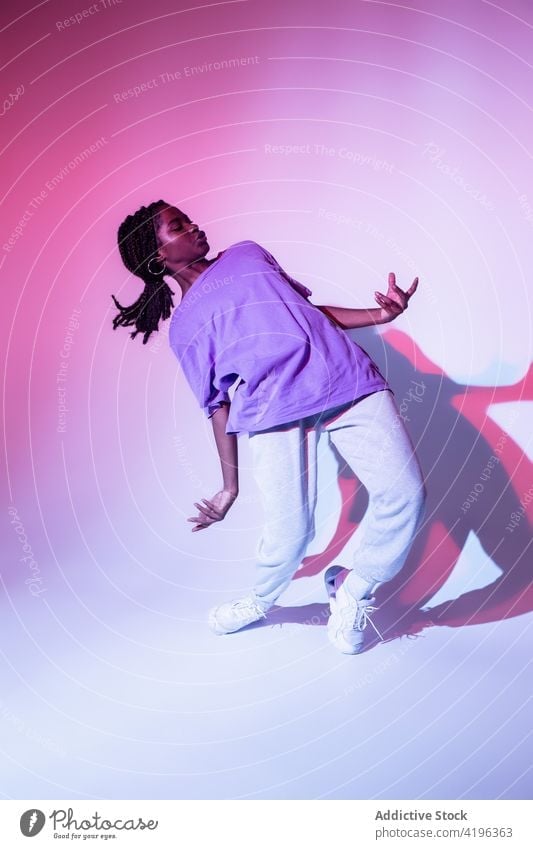 Ausdrucksstarker schwarzer Teenager tanzt ausdrucksstark im bunten Studio Mädchen Tanzen Hip-Hop ausführen Choreographie Energie urban Freestyle cool Tänzer