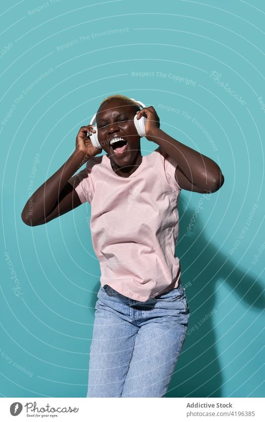 Aufgeregte schwarze Frau mit Kopfhörern Musik Afrikanisch charismatisch expressiv Audio Gerät Tanzen Gesang Apparatur froh Amerikaner Melodie Kurze Haare