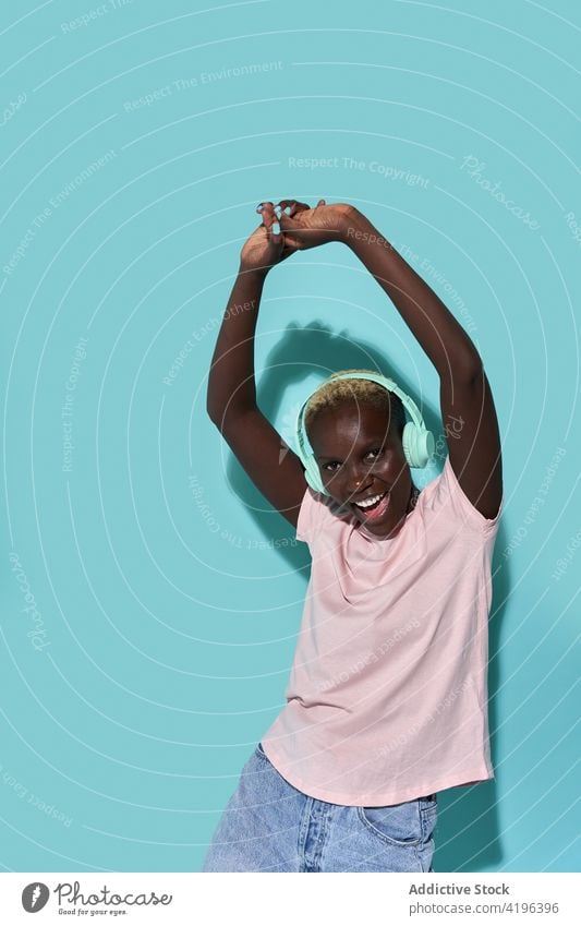 Aufgeregte schwarze Frau mit Kopfhörern Musik Afrikanisch charismatisch expressiv Audio Gerät Gesang Tanzen Apparatur Spaß haben froh Amerikaner Melodie