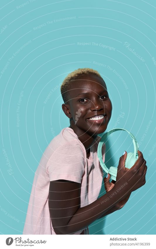 Aufgeregte schwarze Frau mit Kopfhörern Musik Afrikanisch charismatisch expressiv Audio Gerät Gesang Apparatur froh Amerikaner Melodie Kurze Haare zuhören Glück