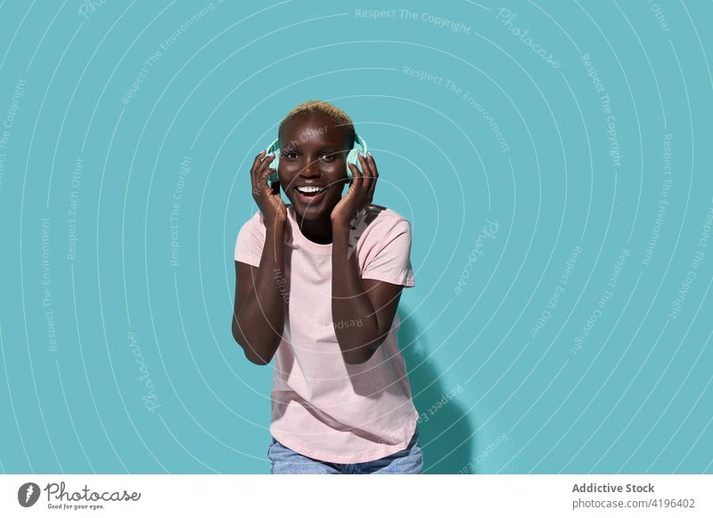 Aufgeregte schwarze Frau mit Kopfhörern Musik Afrikanisch charismatisch expressiv Audio Gerät Gesang Apparatur froh Amerikaner Melodie Kurze Haare zuhören Glück