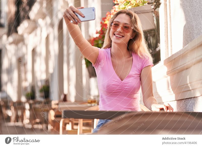Lächelnde Teenagerin, die ein Selfie mit ihrem Smartphone macht und auf der Straße sitzt Frau benutzend unter Surfen Texten Anschluss positiv zuschauen blättern