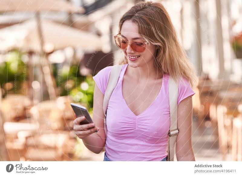 Positive Teenagerin mit Smartphone in einem Straßencafé Frau benutzend zuschauen froh Mobile sorgenfrei reisen Anschluss Funktelefon positiv Optimist digital
