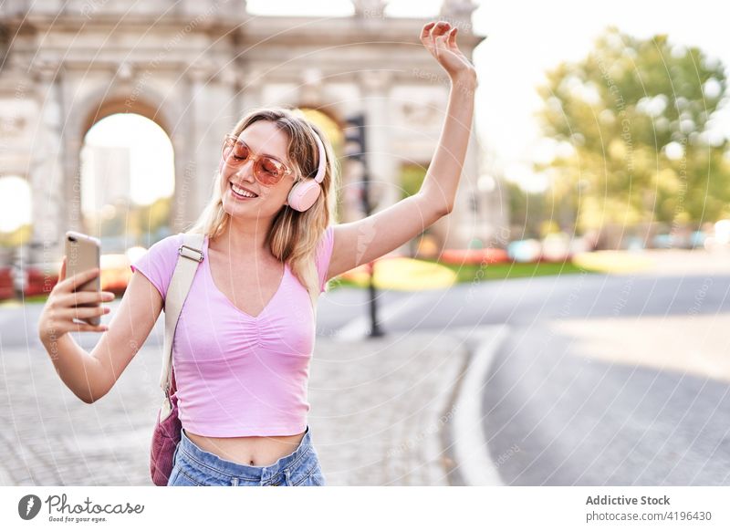 Begeisterte Teenagerin macht Selfie mit Smartphone Frau heiter benutzend Musik Kopfhörer zuhören Sightseeing Gerät Selbstportrait Sonnenbrille Telefon Optimist