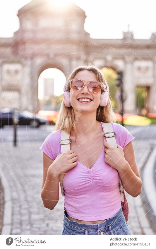Fröhliche junge Frau, die ihren Urlaub auf einer Straße in der Stadt genießt Glück Teenager genießen Kopfhörer Feiertag reisen Spaß sorgenfrei Vergnügen heiter