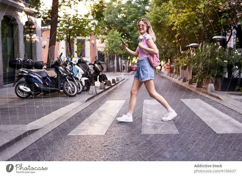 Positiver Teenager-Tourist surft auf seinem Smartphone, während er die Straße auf dem Zebrastreifen überquert Frau Fußgänger prüfen benutzend durchkreuzen Route